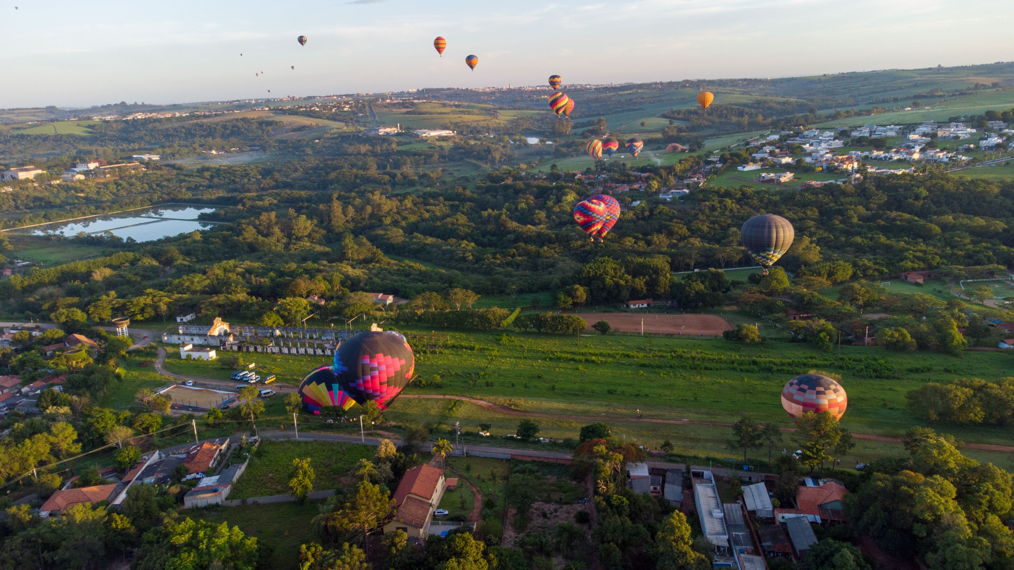 A landscape with hot air balloons, a river, and scattered buildings.