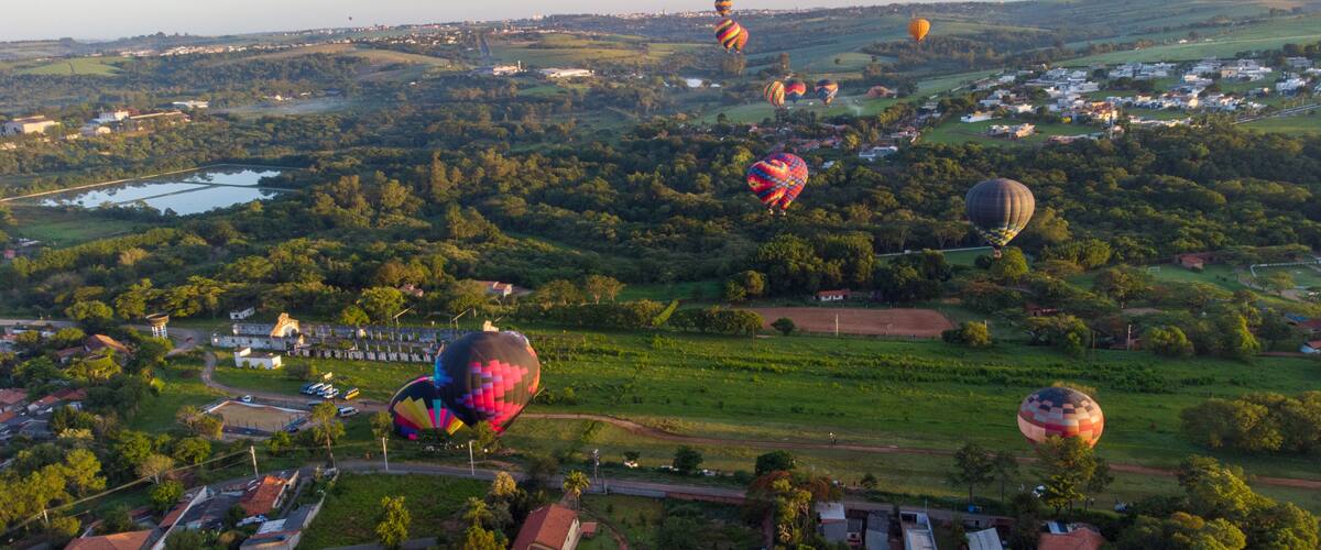 A landscape with hot air balloons, a river, and scattered buildings.