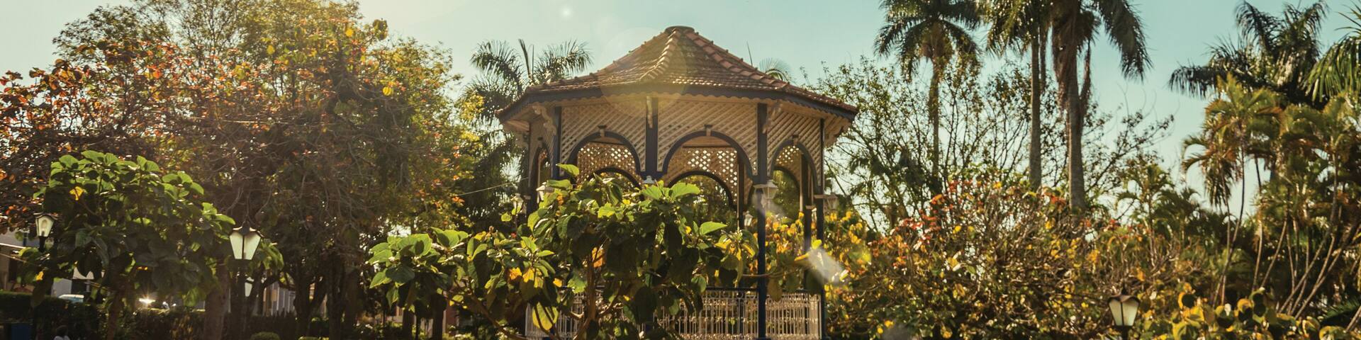 Old and colorful gazebo of square in the middle of verdant garden full of trees, in a bright sunny day at São Manuel. A cute little town in the countryside of São Paulo State. Southeast Brazil.