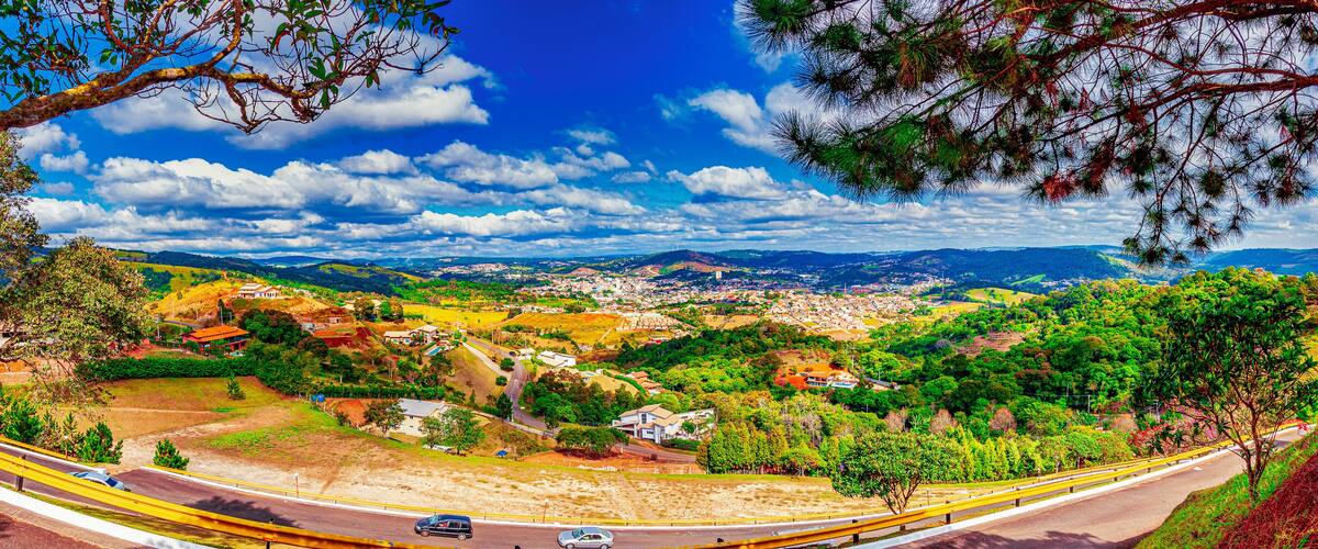 Une vue panoramique d’une ville nichée dans une vallée, traversée par une route sinueuse qui se détache dans le paysage.