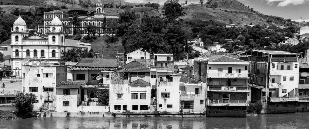 A riverside town with historic buildings, a church, and a hill with a church on top.