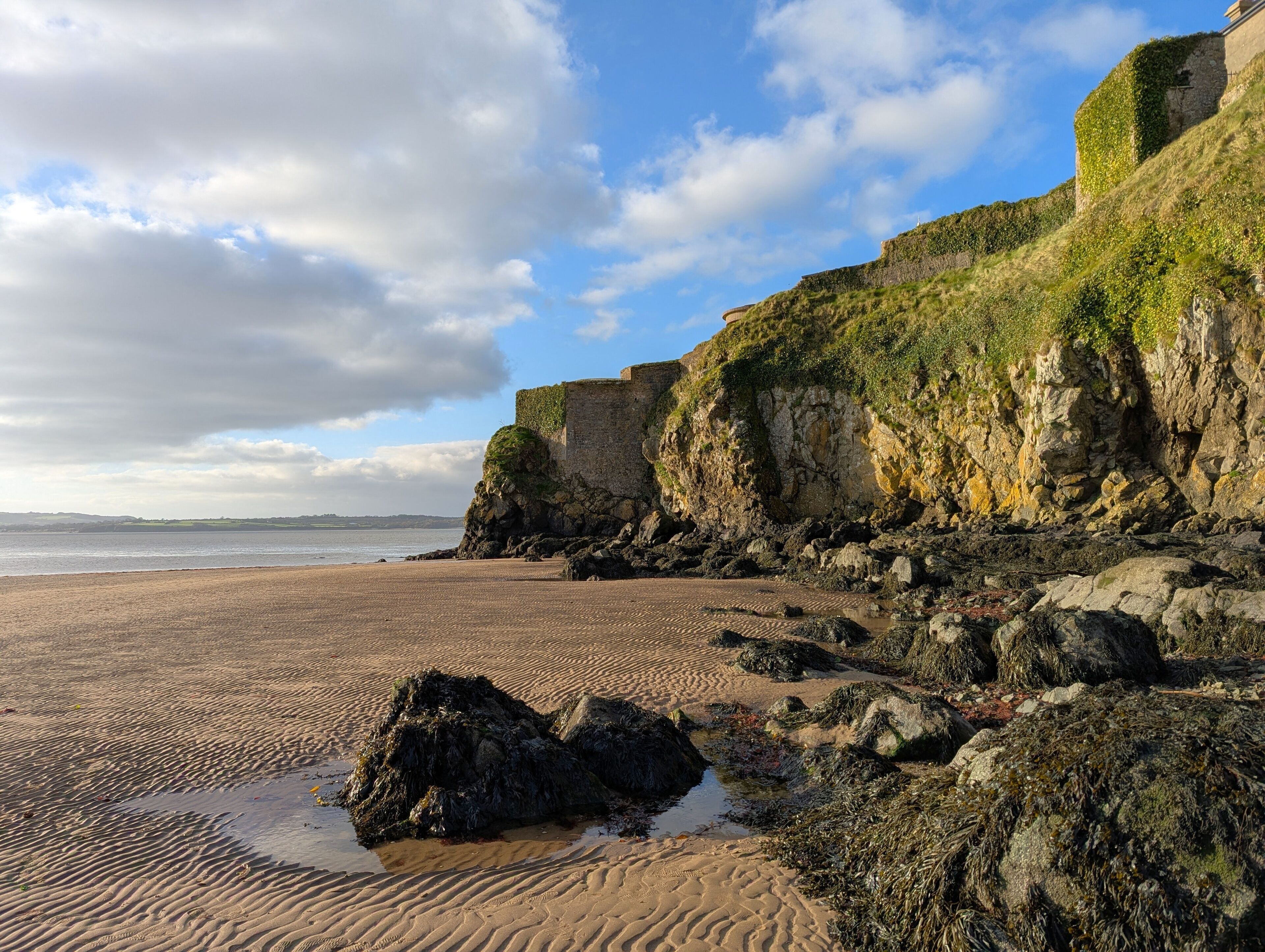 A sandy beach with rocky cliffs and a clear sky.