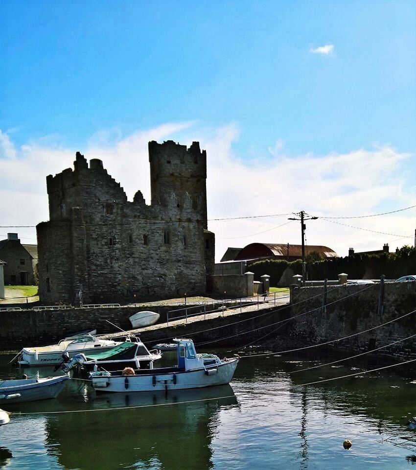 A historic castle and moored boats in a harbor.