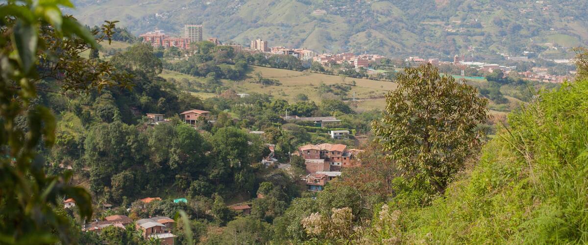 A mountainous landscape with scattered buildings and greenery.