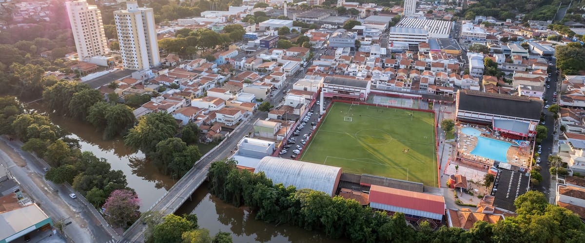 An aerial view of a town with a river, a sports field, and several buildings.