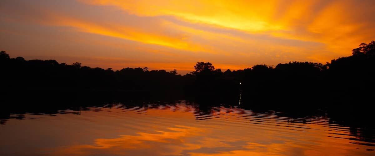 A sunset over a calm lake with reflections of the sky.