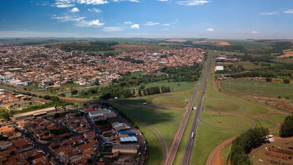 An aerial view of a city with a highway, residential areas, and surrounding greenery.