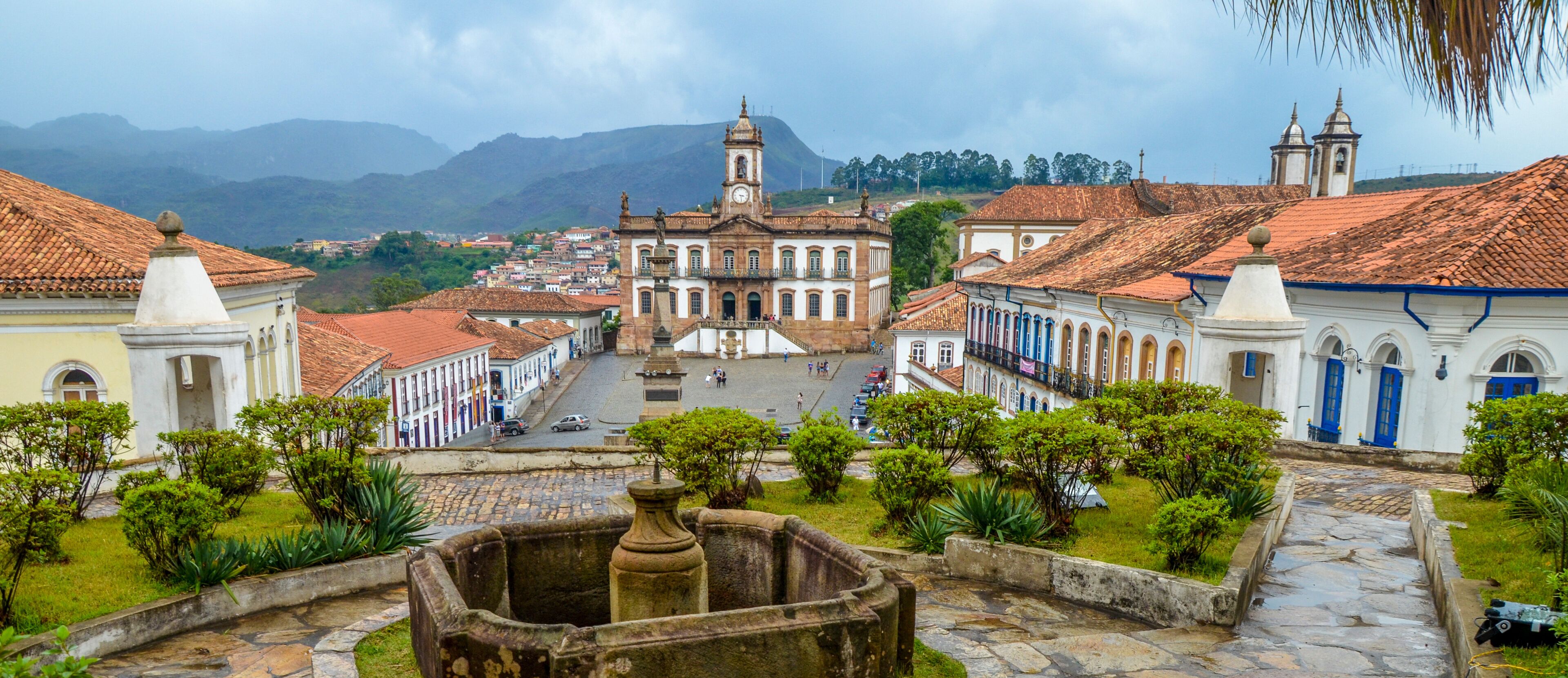 A historic square with a prominent church, cobblestone streets, and lush greenery.