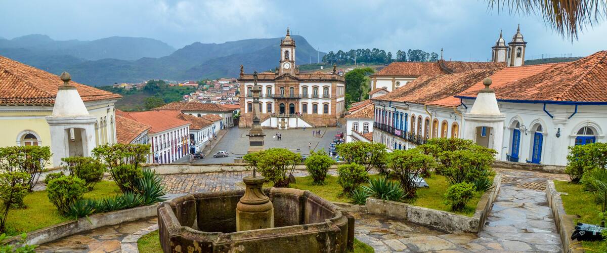 A historic square with a prominent church, cobblestone streets, and lush greenery.