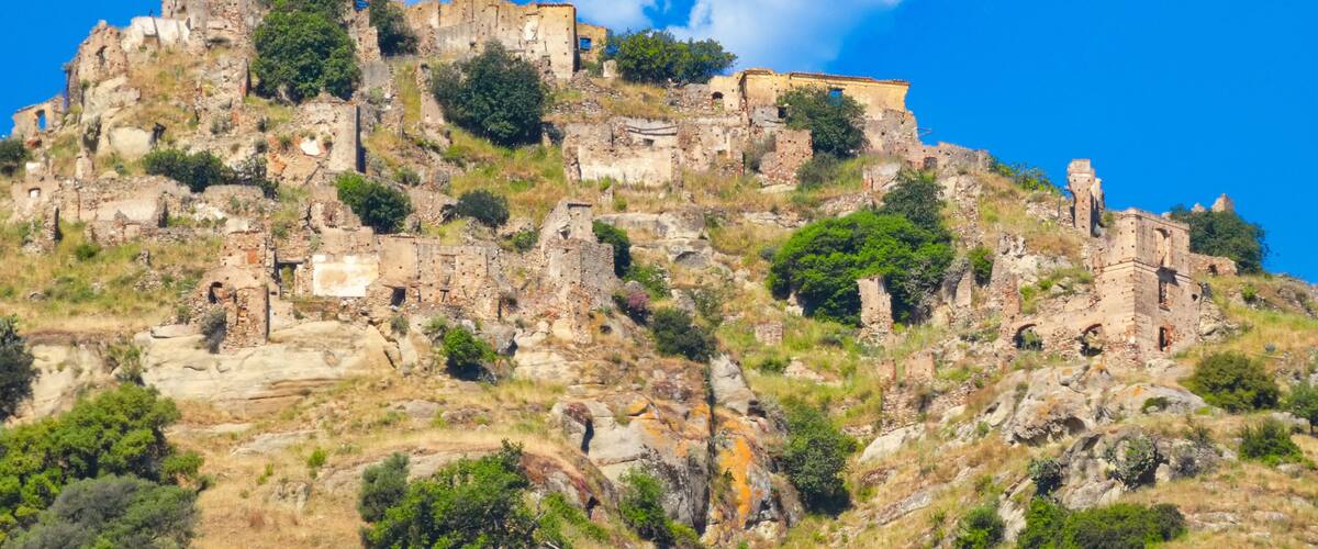 A hilltop with ancient ruins and greenery under a clear blue sky.
