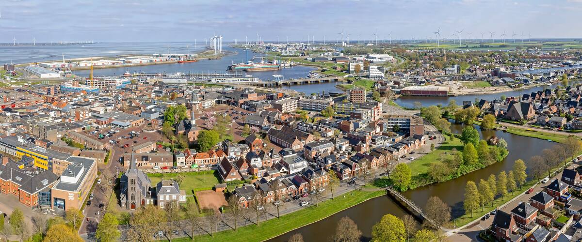 A coastal city with a river, wind turbines, and residential areas.