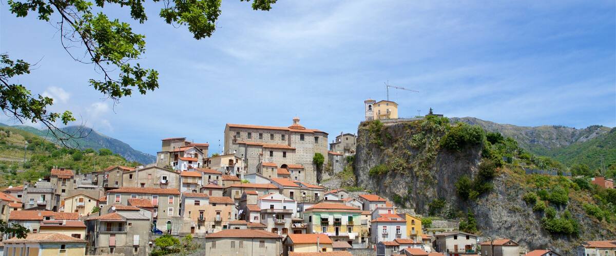 A hillside town with terracotta-roofed buildings, a prominent church, and a rocky cliff.