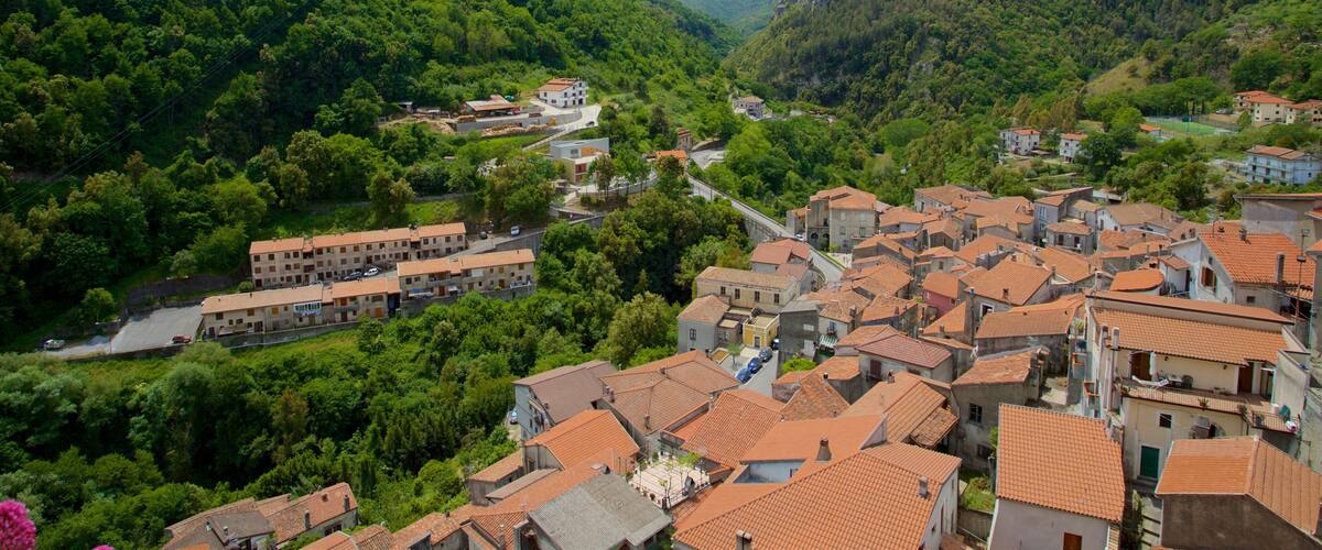 Un pueblo enclavado en un valle, con edificios de tejados terracota, rodeado de colinas verdes y exuberantes.