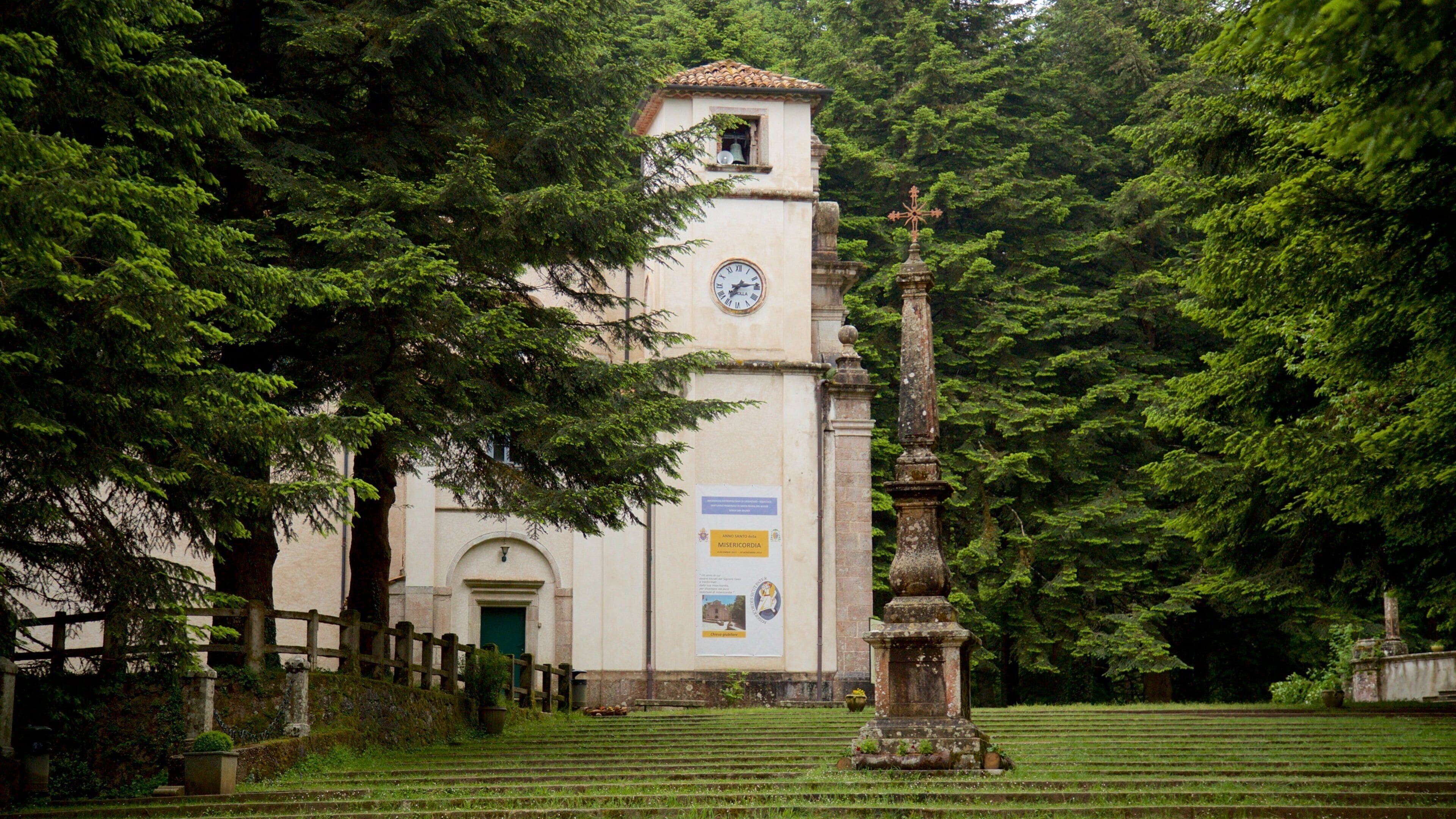 A church with a clock tower surrounded by lush greenery.