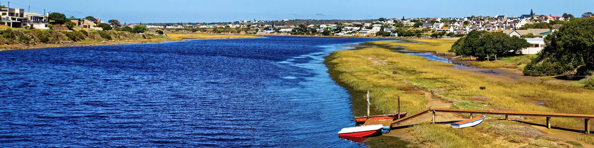 Description
Broad Goukou river estuary with small jetty and boat flowing through the town of Still Bay in the Western Cape, South Africa