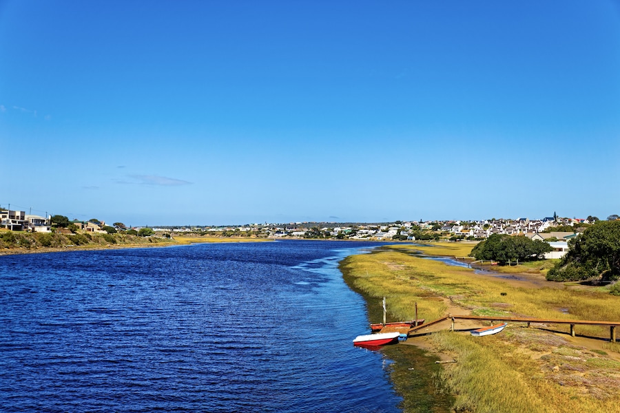 Description
Broad Goukou river estuary with small jetty and boat flowing through the town of Still Bay in the Western Cape, South Africa