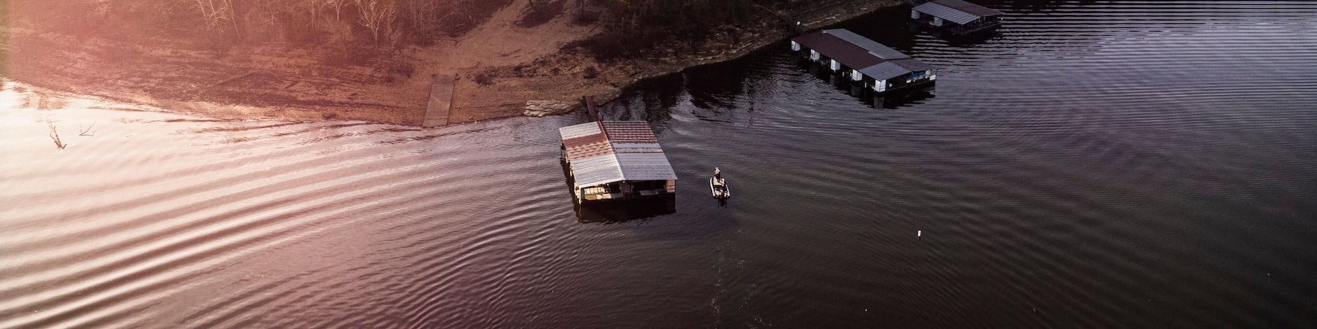 An aerial view of a river with floating docks and a forested shoreline.