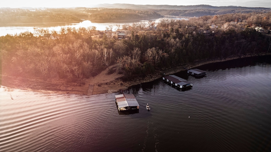 An aerial view of a river with floating docks and a forested shoreline.