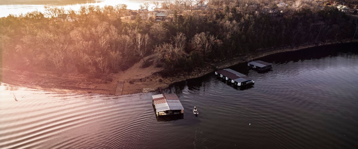 An aerial view of a river with floating docks and a forested shoreline.