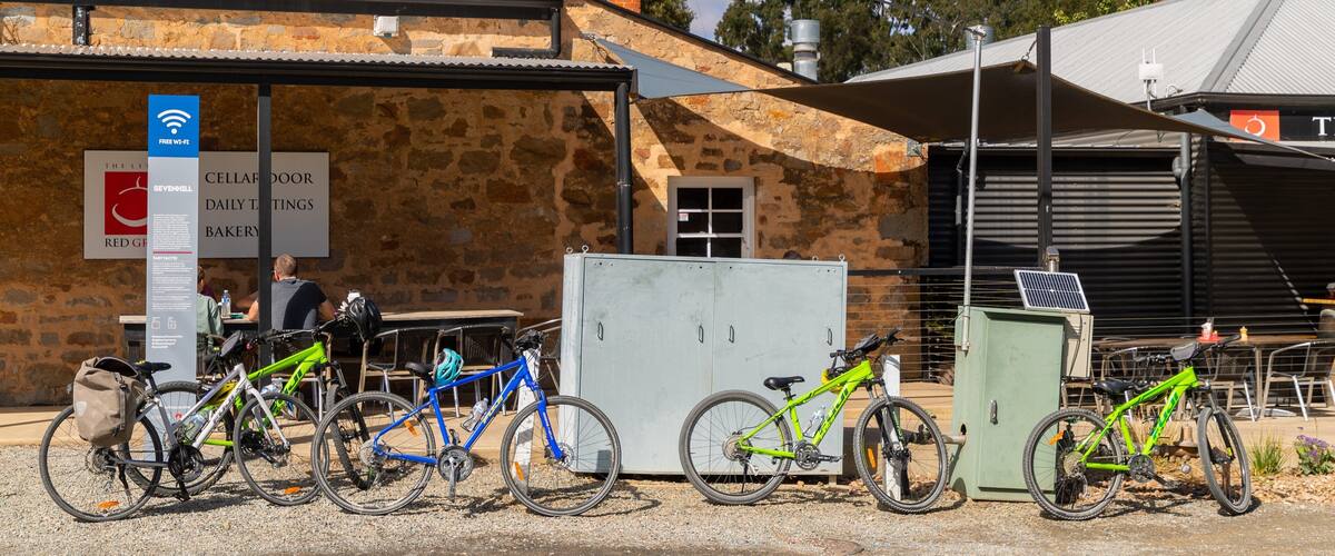 A stone building with a corrugated metal roof, bicycles parked in front, and a sign indicating free Wi-Fi.