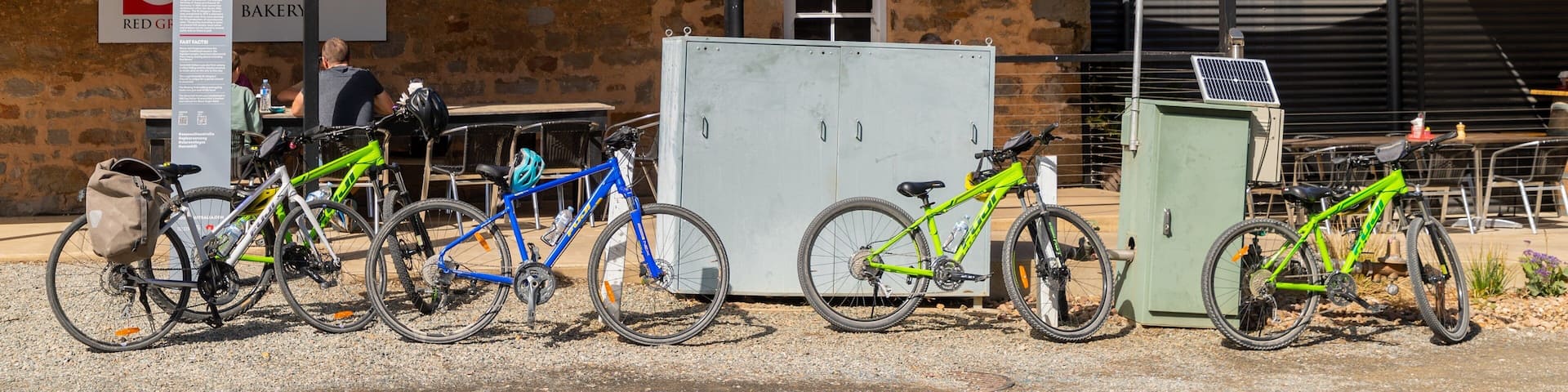 A stone building with a corrugated metal roof, bicycles parked in front, and a sign indicating free Wi-Fi.