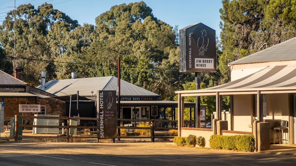 A roadside with a hotel named 'SEVENHILL HOTEL' and 'JIM BARRY WINES'. There is a sign for 'HOTEL PARKING AT REAR' and a building with a sign 'LITTLE RED GRAPE'.