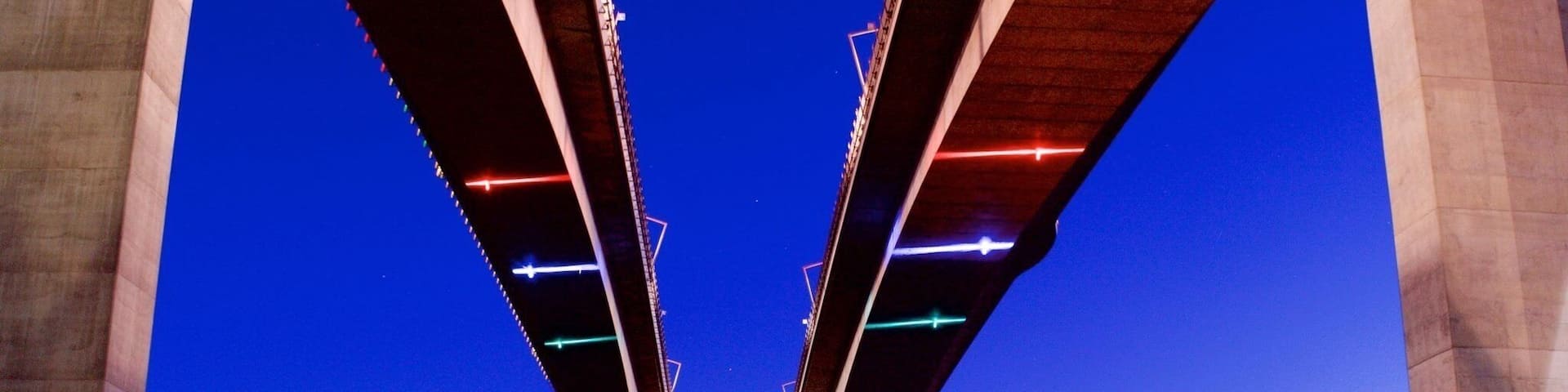 A large bridge with multiple arches over a calm body of water at dusk.