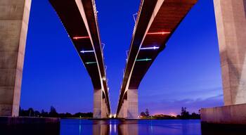 A large bridge with multiple arches over a calm body of water at dusk.