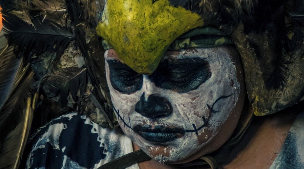 A local musician dressed as a dead Eagle Warrior sings and plays the drums, asking the spirits to visit the living and take the offerings from the altars.