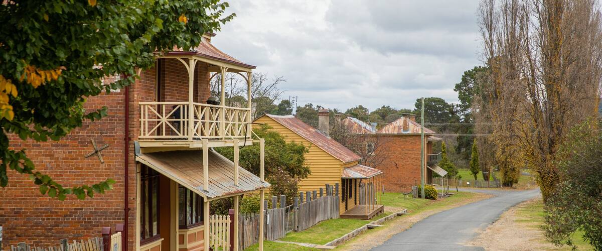 A quiet street lined with traditional brick houses, a wooden fence, and a clear road.