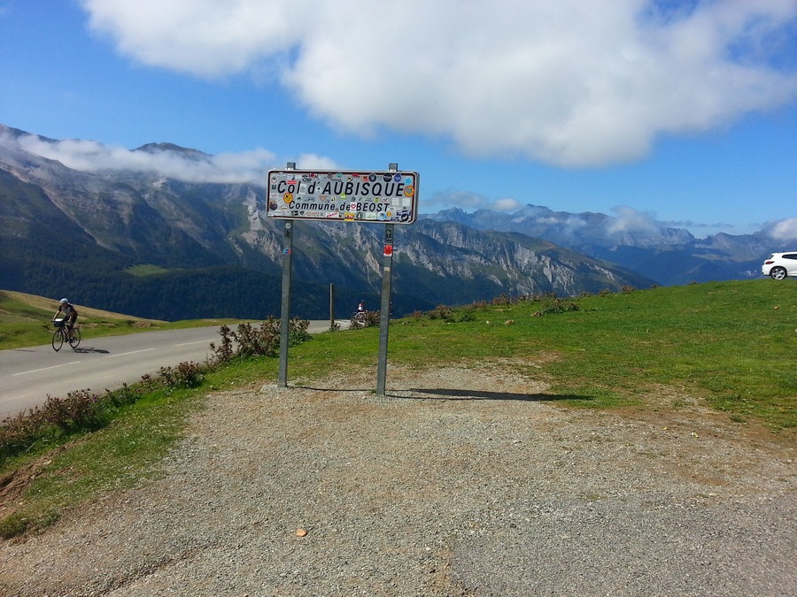 Un panneau indicateur orné d’autocollants, un cycliste et un paysage de montagne.