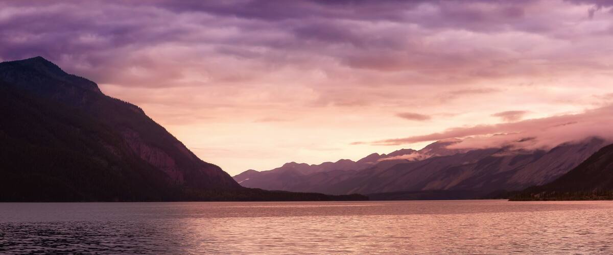Beautiful Panoramic View of Muncho Lake in the Canadian Northern Rockies during a cloudy sunrise. Taken in British Columbia, Canada. Nature Background Panorama