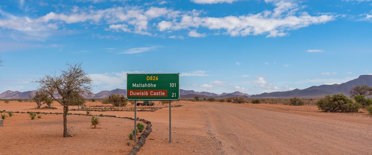 A road sign in a desert landscape with mountains in the background.