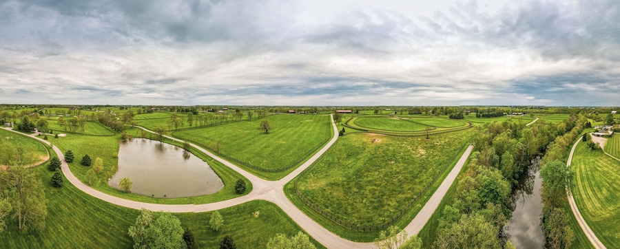 Un paysage rural avec une route sinueuse, un étang et une rivière.