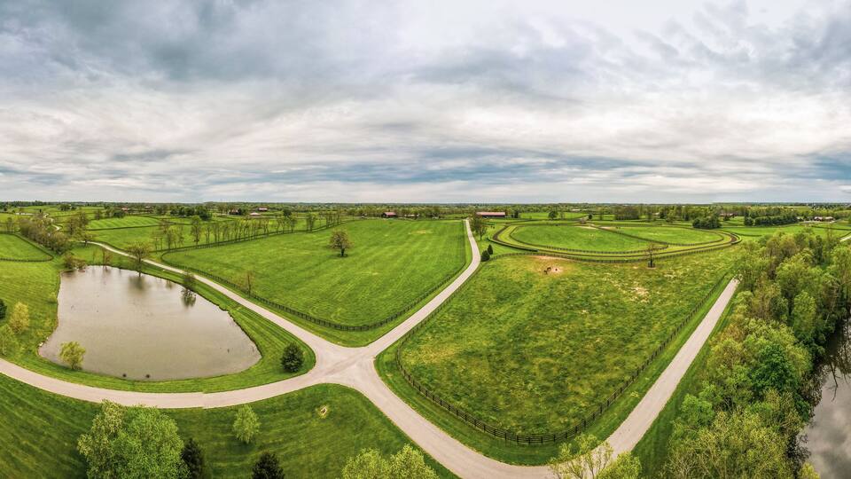 A rural landscape with a winding road, a pond, and a river.