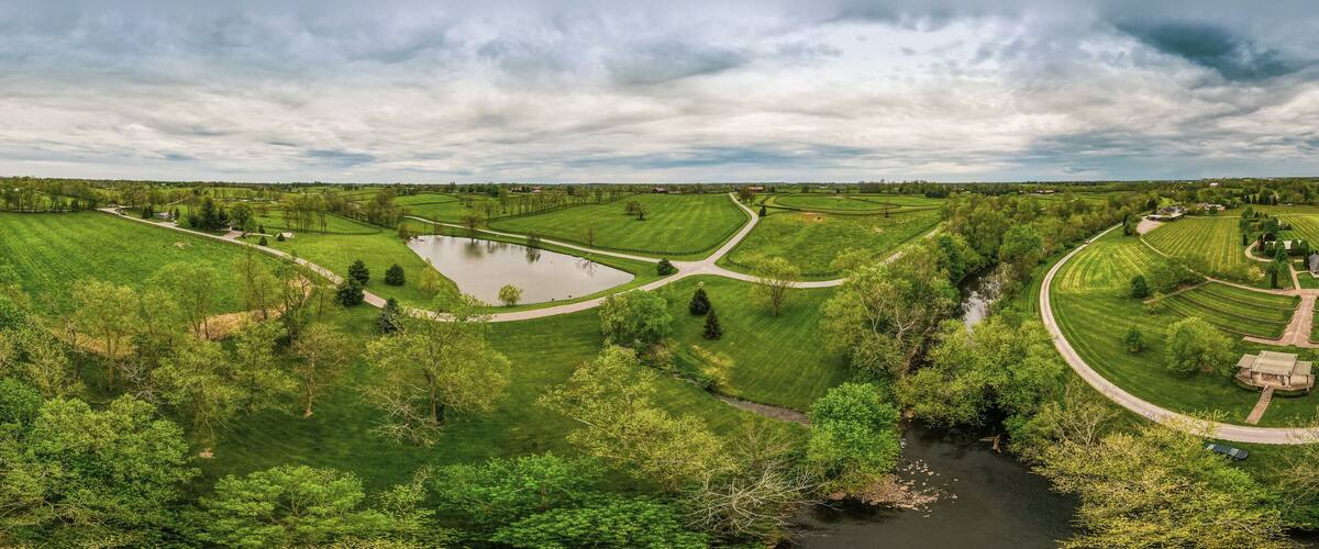 A river winding through a lush green landscape with fields and trees.