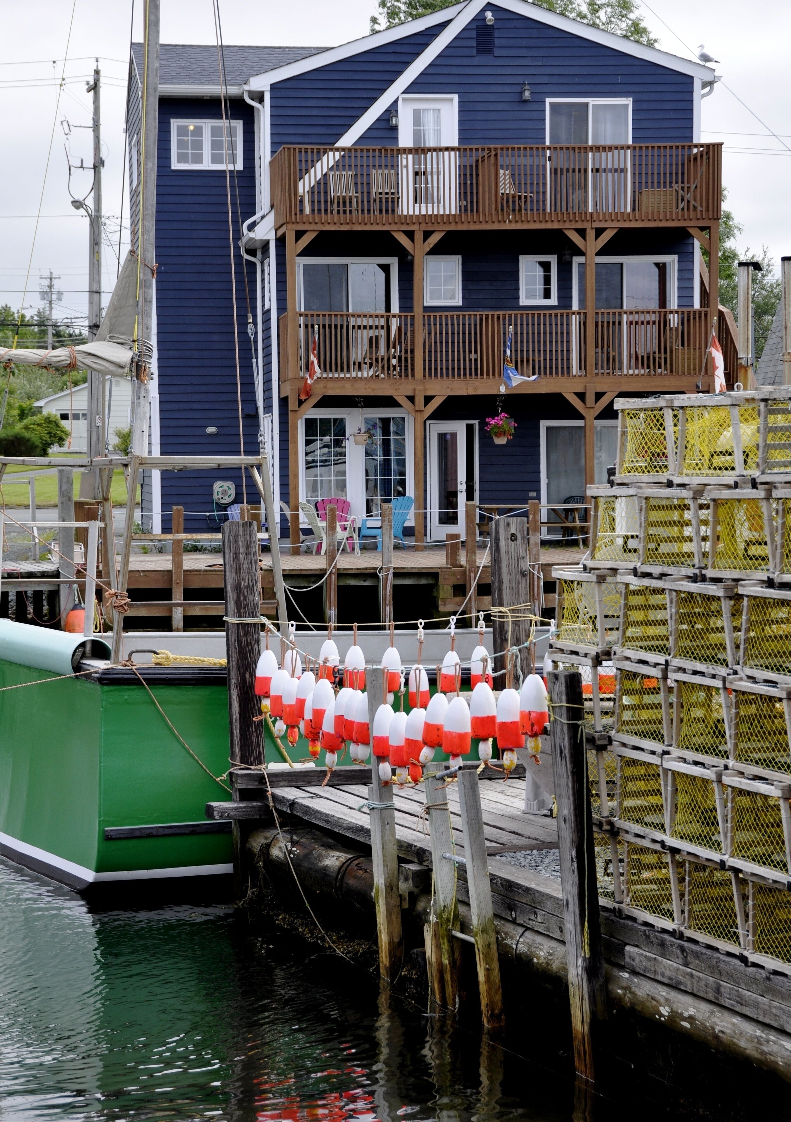 Un muelle con boyas y una casa con balcón.
