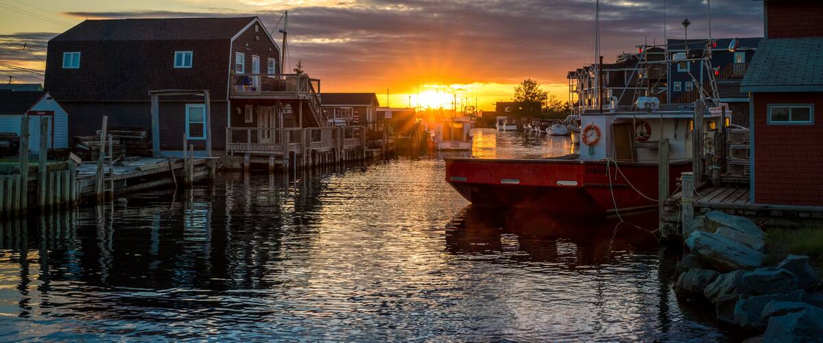 Un tramonto su un porto con barche, moli di legno e edifici.