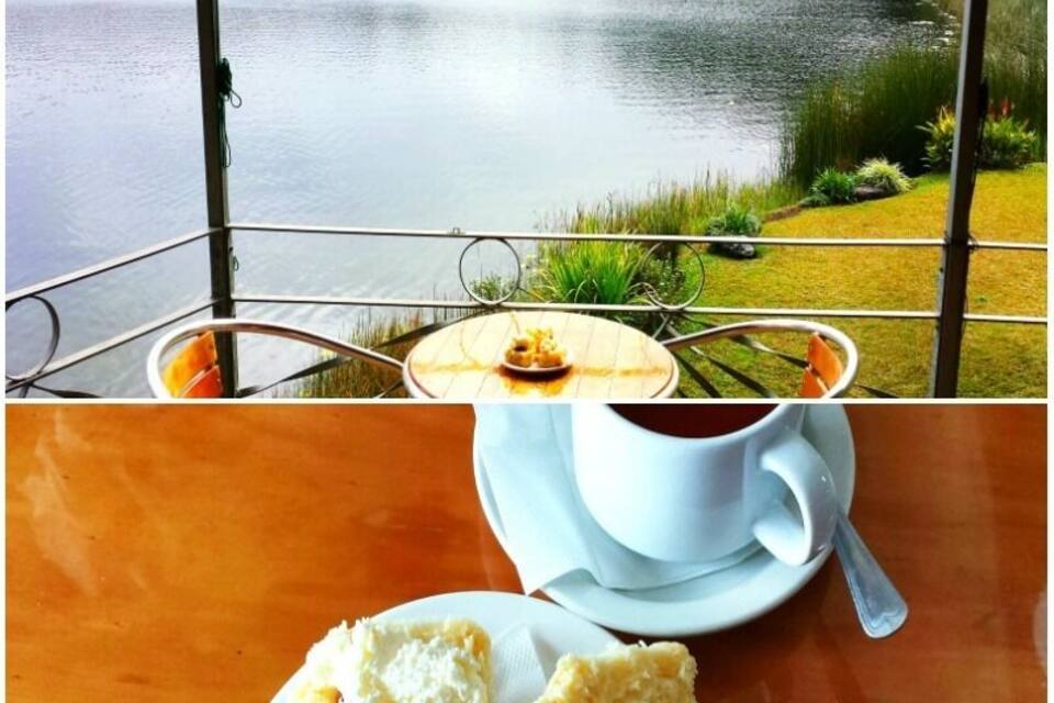Vista para o lago com uma mesa, uma xícara de café e um pastel.