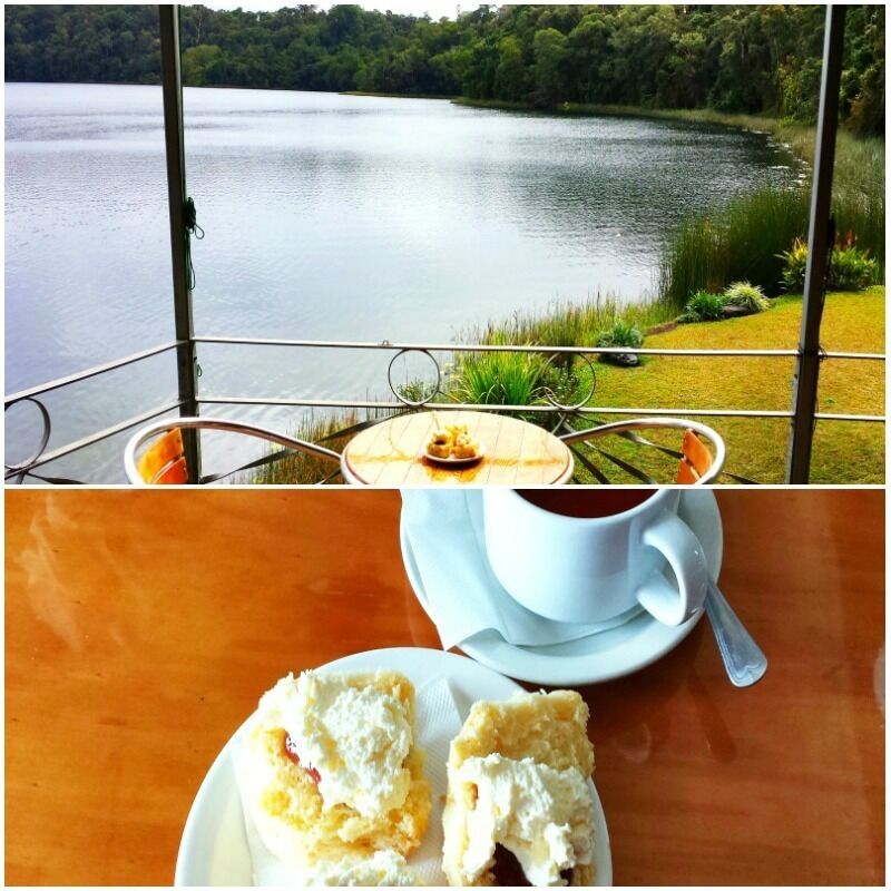 A lakeside view with a table featuring a cup of coffee and a pastry.