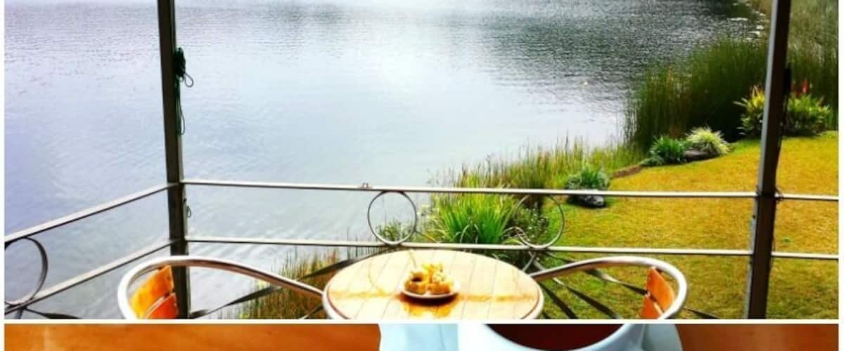 A lakeside view with a table featuring a cup of coffee and a pastry.