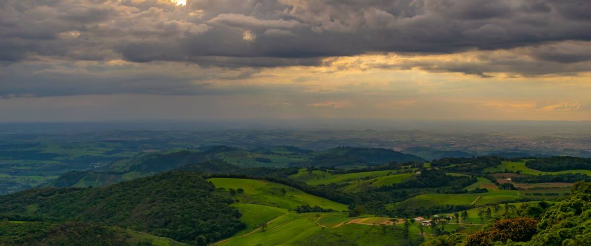 A landscape with rolling hills, a winding road, and a distant view of a town.