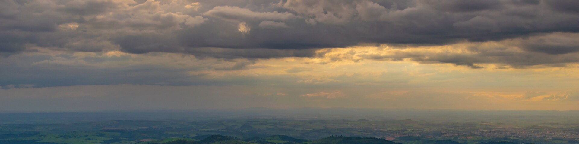 A landscape with rolling hills, a winding road, and a distant view of a town.