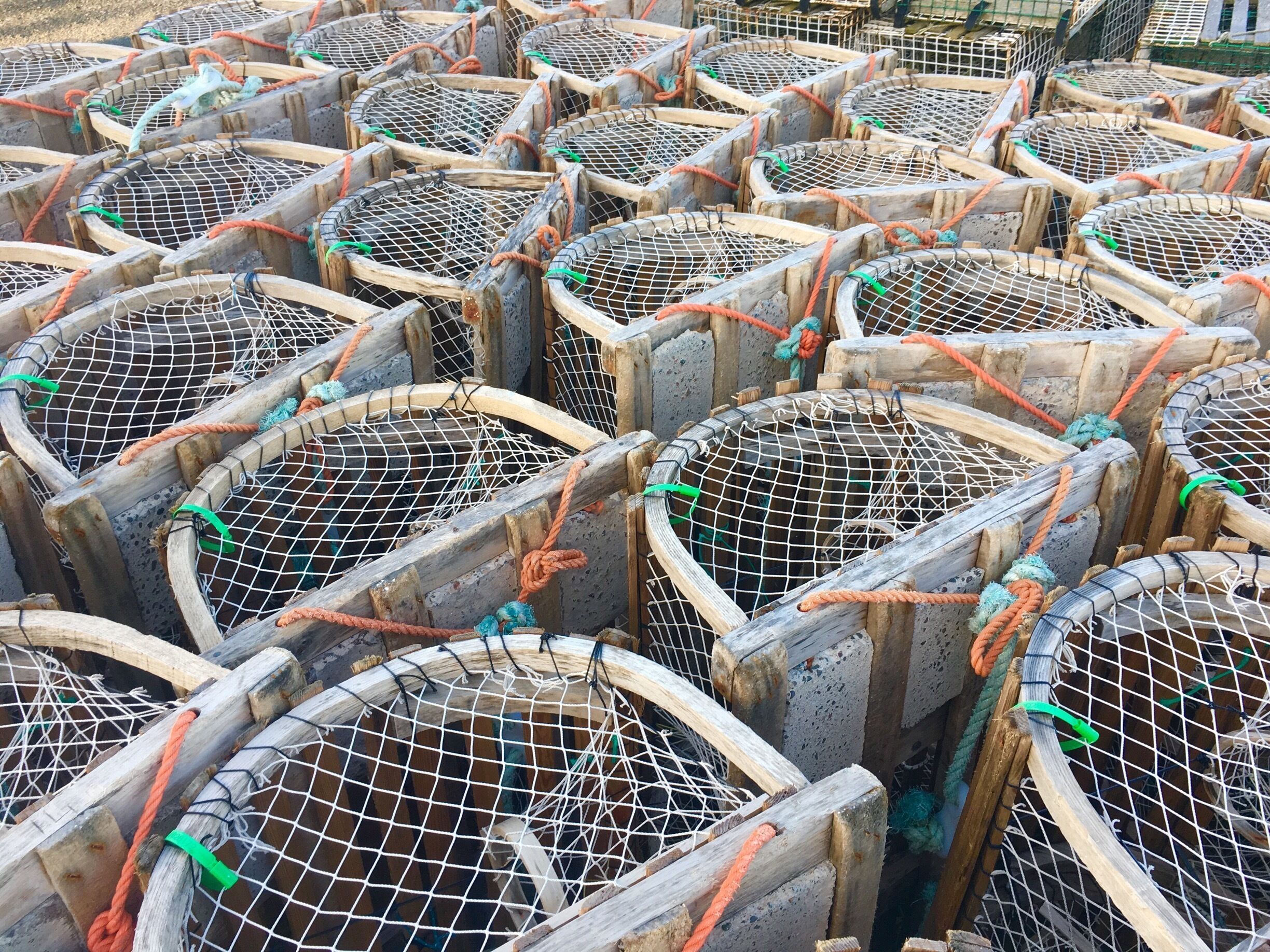 A collection of wooden lobster traps with metal mesh and ropes.