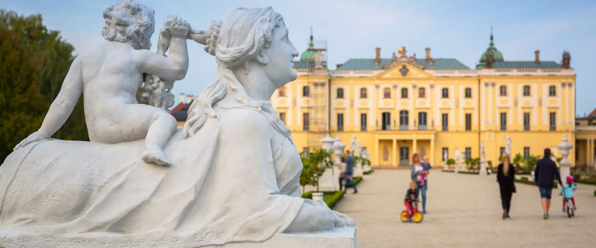 A classical statue in a public square with a historic building in the background.