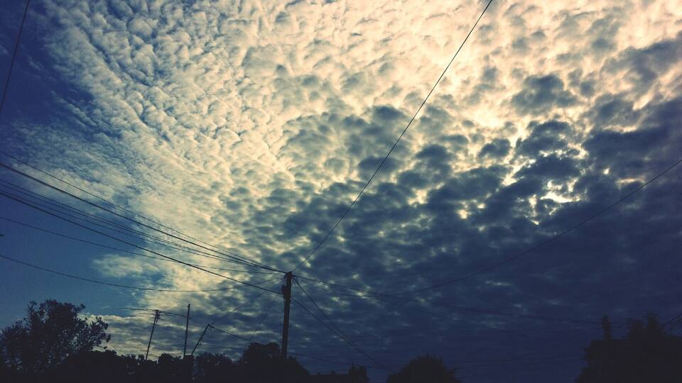 A sky filled with clouds and power lines.