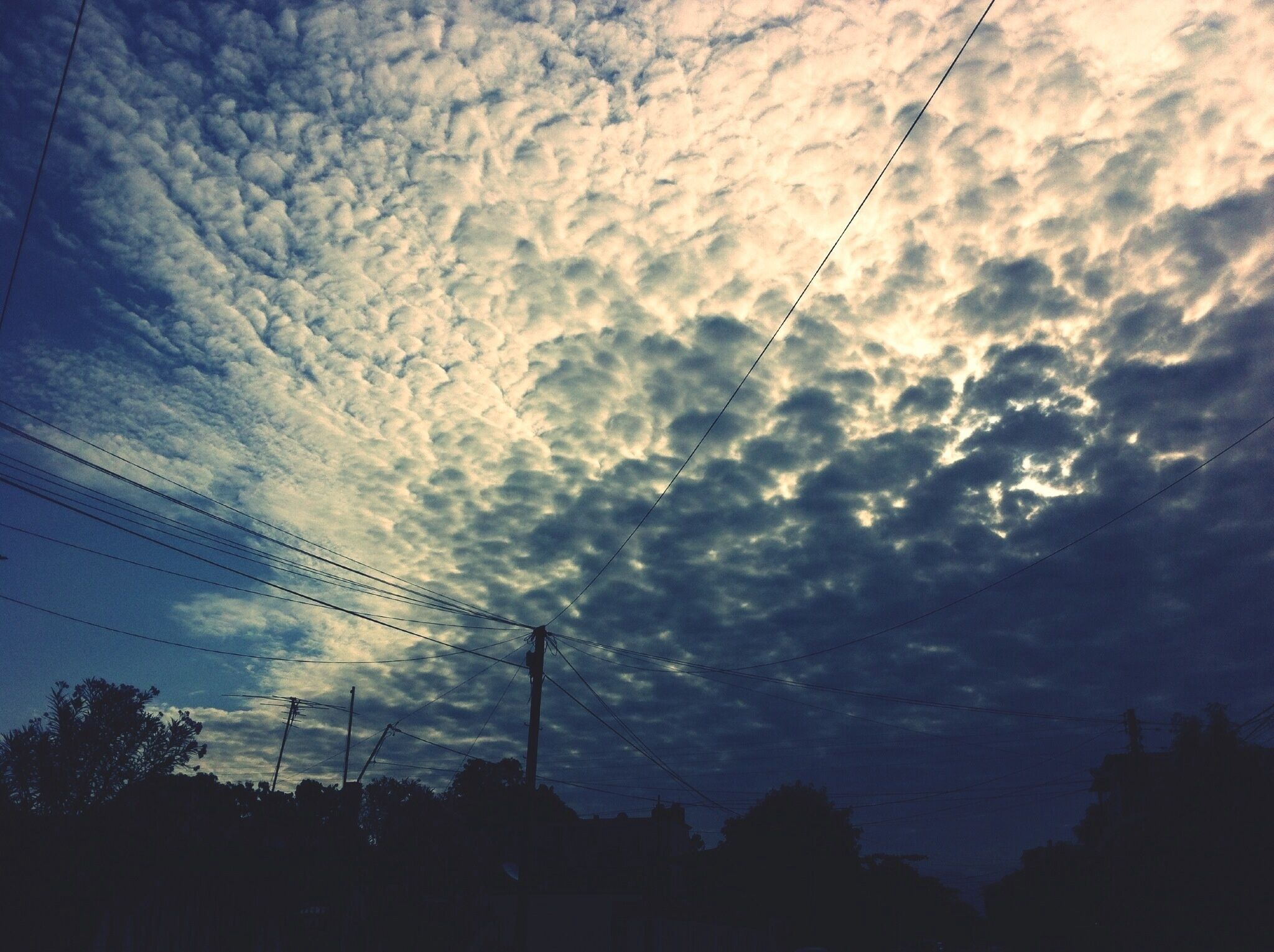 A sky filled with clouds and power lines.