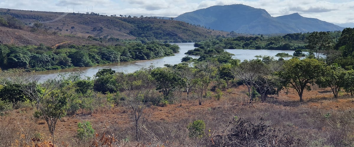 A river winding through a hilly landscape with dense vegetation and a mountain in the background.