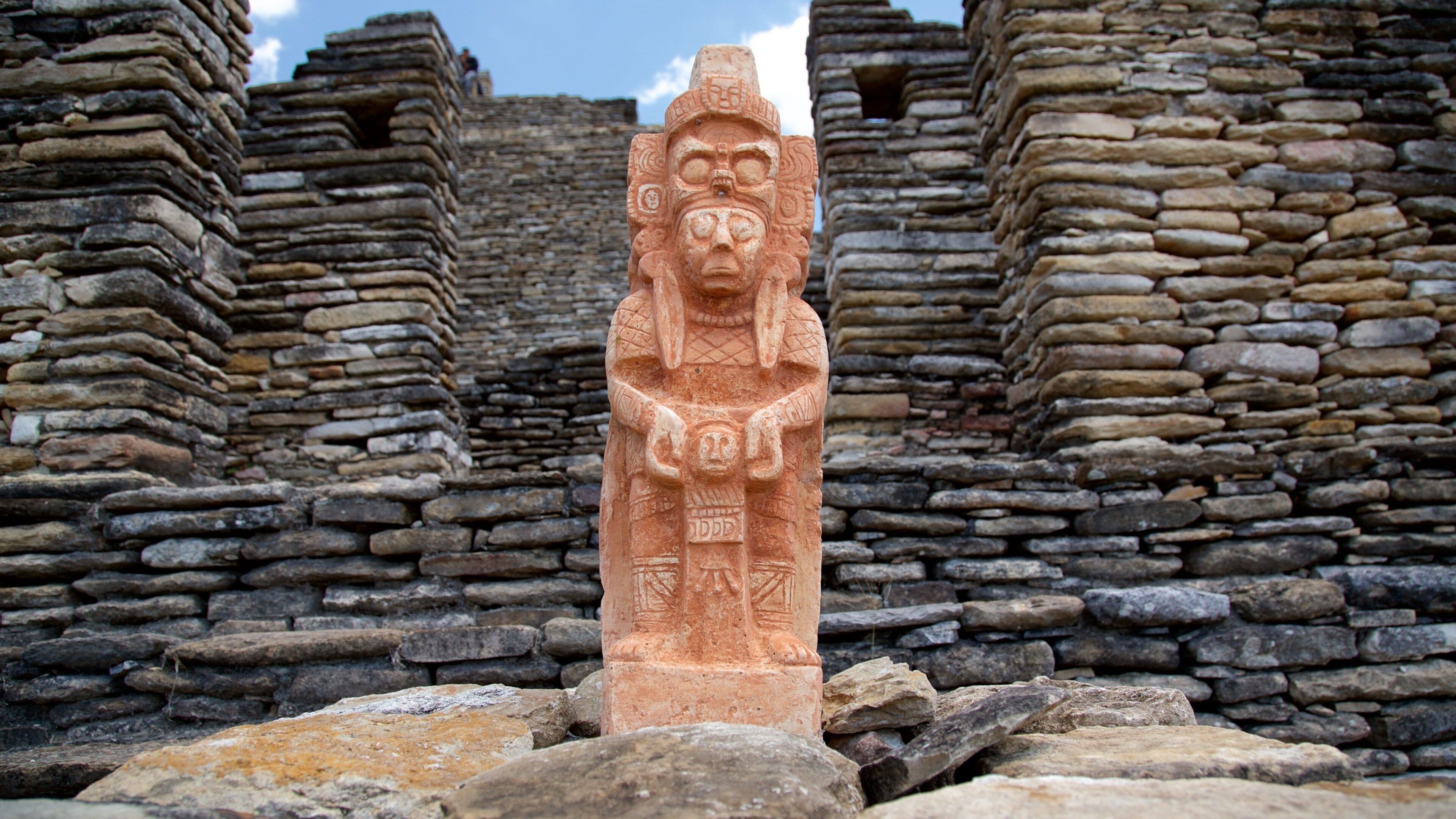 A stone statue in front of ancient stone walls.