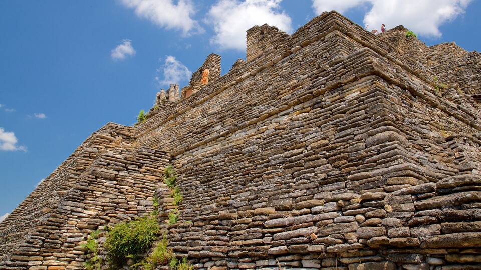 A large stone structure with layered stonework and a clear blue sky.